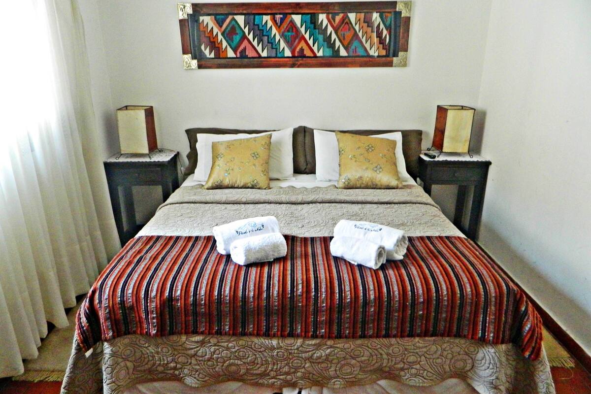 Ein Hotelzimmer mit einem großen Bett, zwei Nachttischen, einem Wandbild und zwei Handtüchern auf dem Bett.