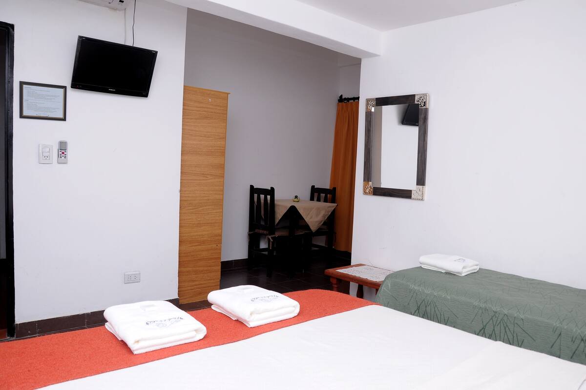 Ein Hotelzimmer mit Bett, Schreibtisch, Stuhl, Fernseher und Spiegel.