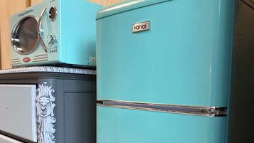 Two vintage refrigerators, one teal and one light blue, with decorative patterns and a brand name visible.