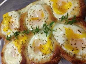 A plate of toast topped with fried eggs and herbs.