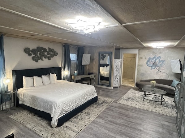 A bedroom with a large bed, a desk, a chair, a sofa, and a coffee table. - Square Inn (Wimberley)