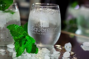 Two glasses of a clear beverage with ice cubes and mint leaves, labeled "Square Inn Stay the Wimberley Way." - Square Inn (Wimberley)