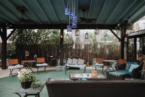An outdoor patio area with wicker furniture, ceiling fans, and hanging lanterns. - Square Inn (Wimberley)
