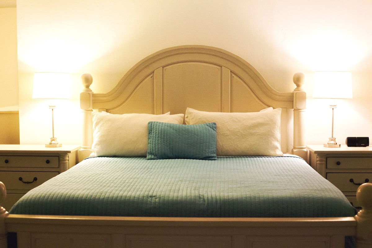 A bed with a headboard, two bedside tables, and two lamps.
