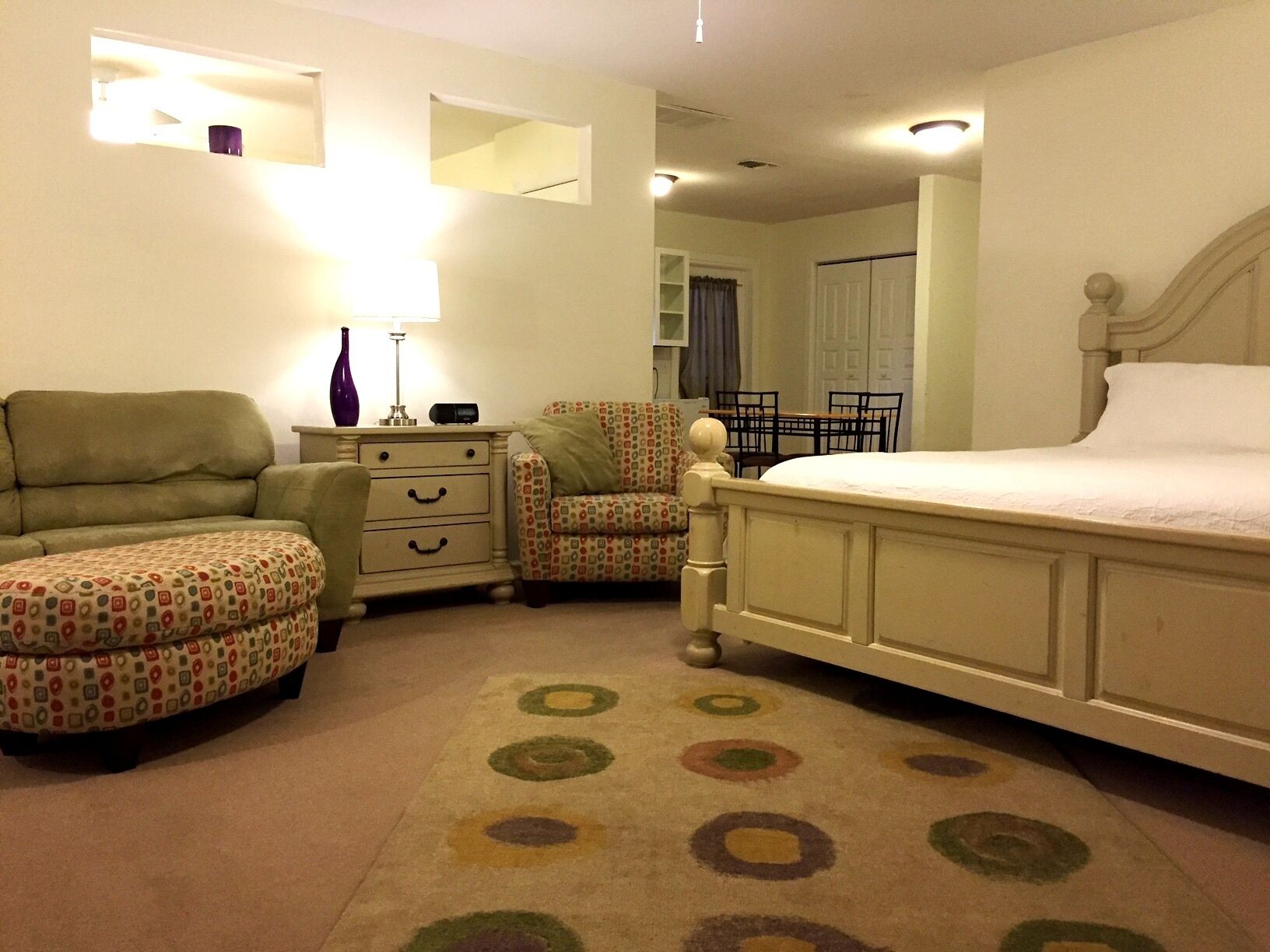 Une chambre à coucher comprenant un lit, une table de chevet, une chaise, une commode et une petite table.