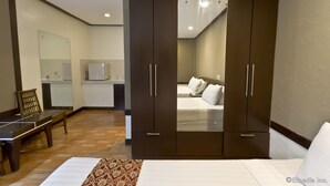 A hotel room with a large wardrobe, a bed, a desk, and a chair. - Holiday Spa Hotel (Cebu City)