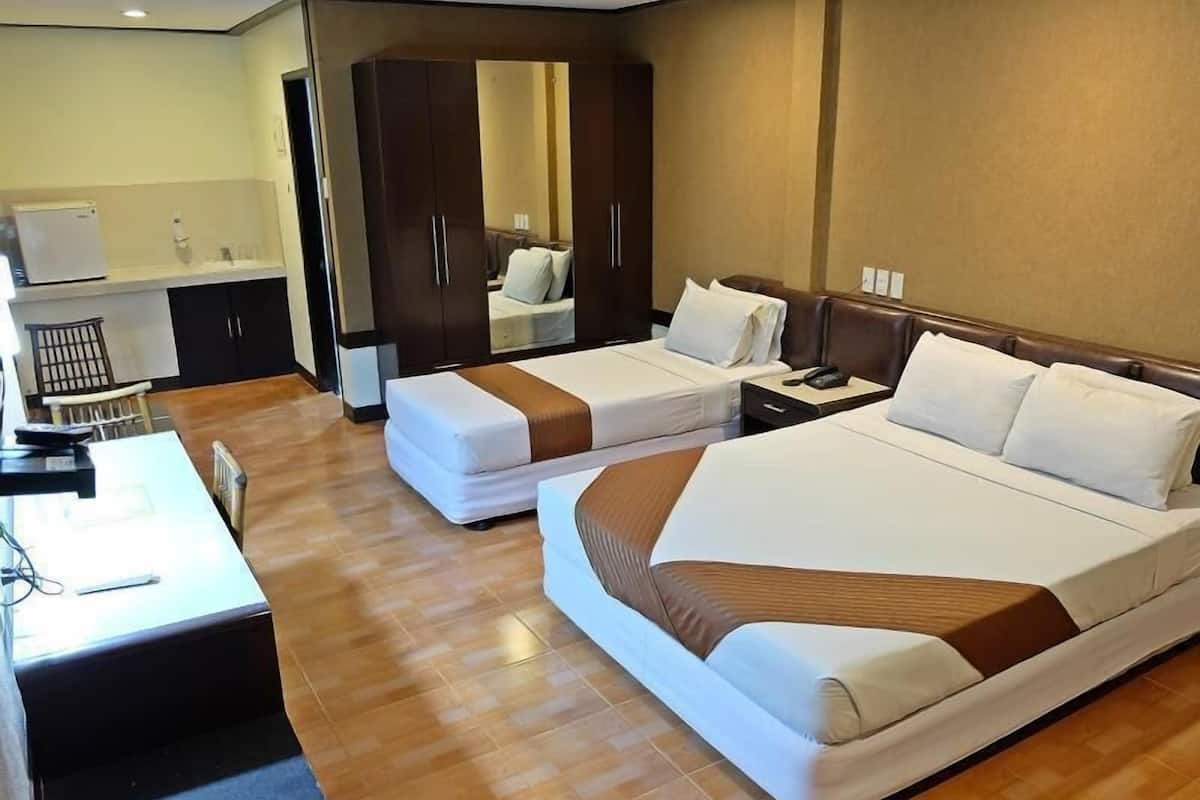 Hotellihuone, jossa on kaksi sänkyä, työpöytä, vaatekaappi ja kylpyhuone.