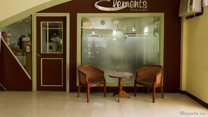 A salon interior with a 'Welcome' sign, two wooden chairs, a small round table, and a frosted glass window. - Holiday Spa Hotel (Cebu City)