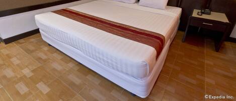 A hotel room with a large bed, a nightstand, and a wall-mounted phone.