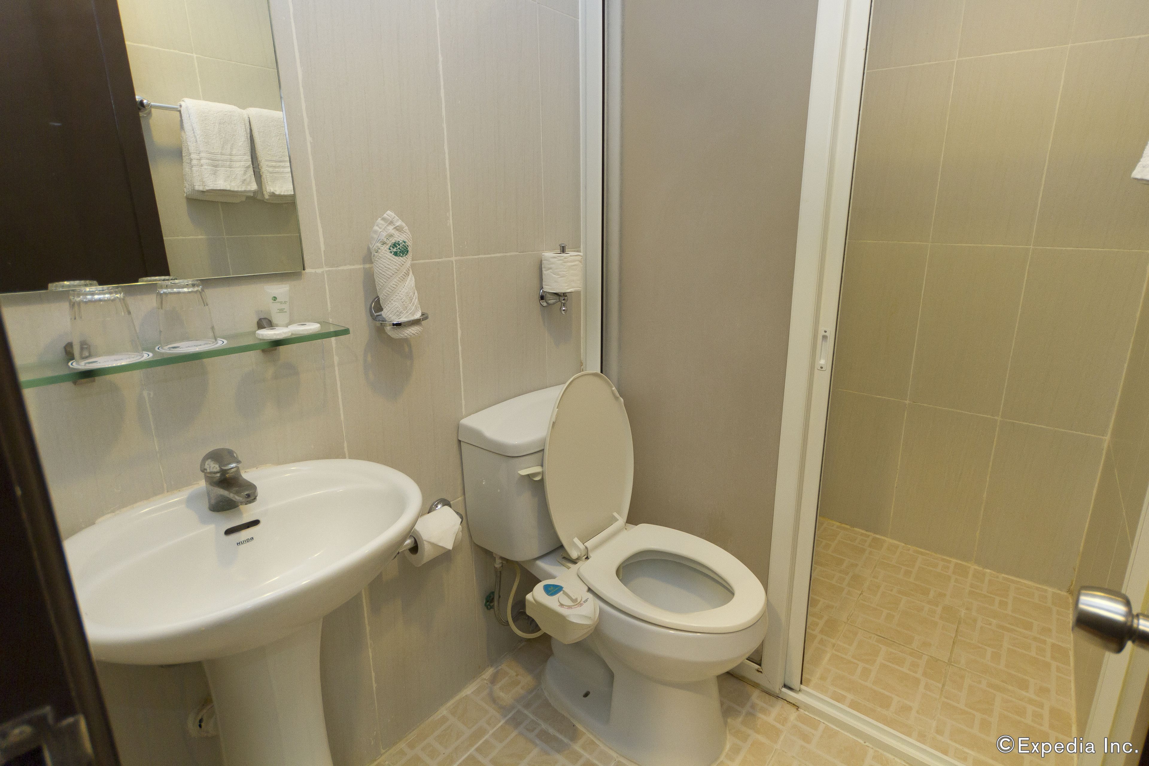 Un baño con lavamanos, inodoro y repisa de vidrio con artículos de aseo.