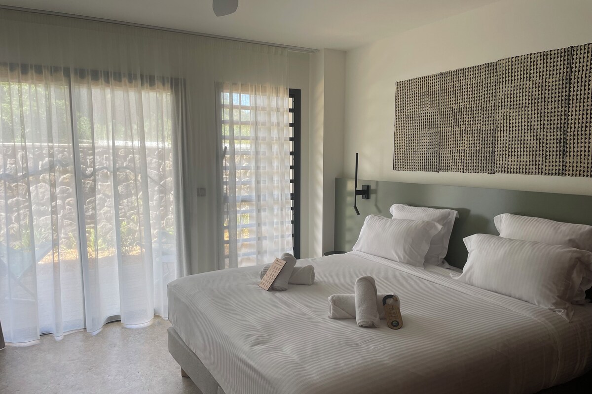 Habitación de hotel con una cama grande, televisor montado en la pared y vistas por la ventana.