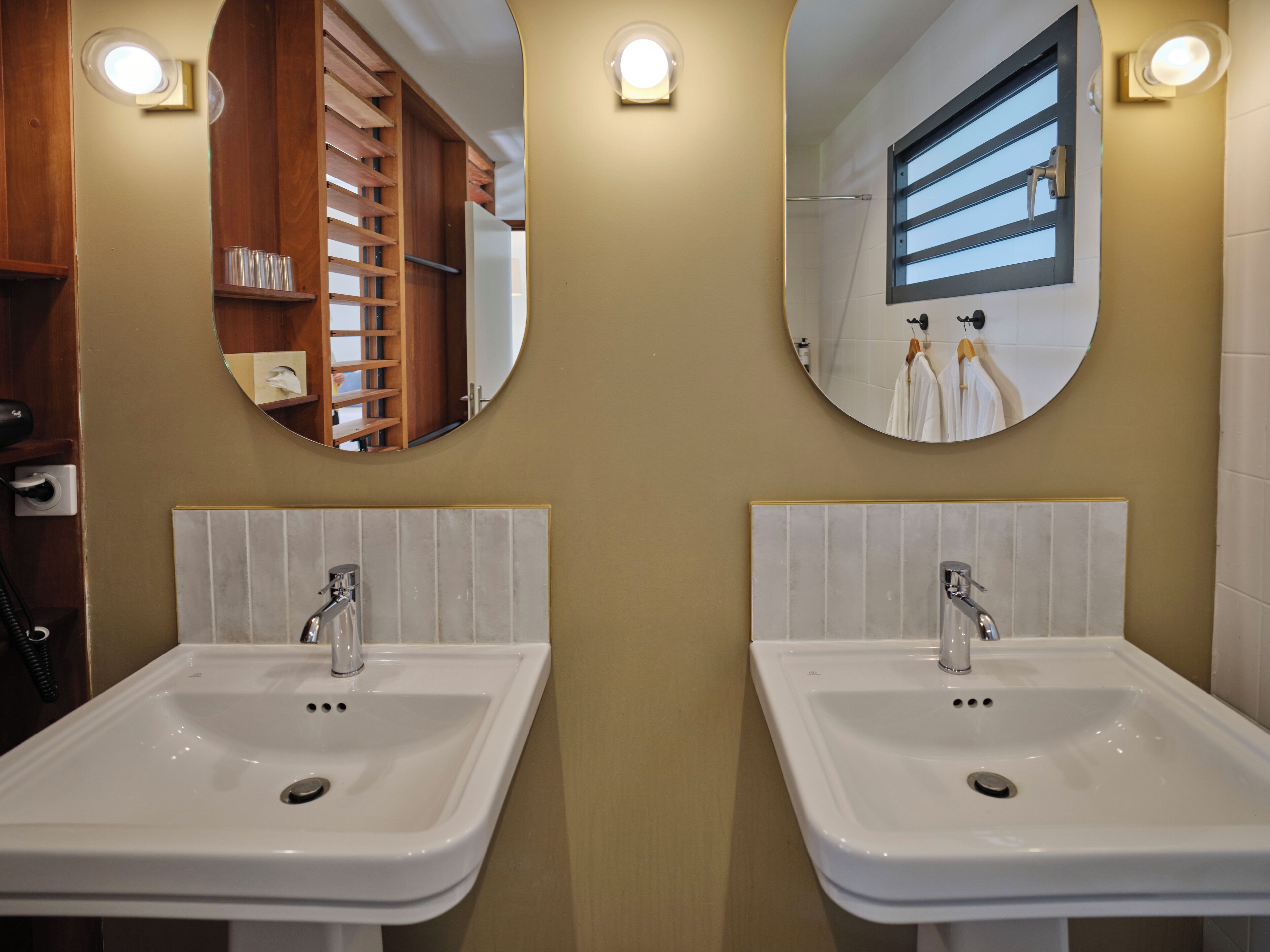 A bathroom with two sinks, wooden shelving, and mirrors.