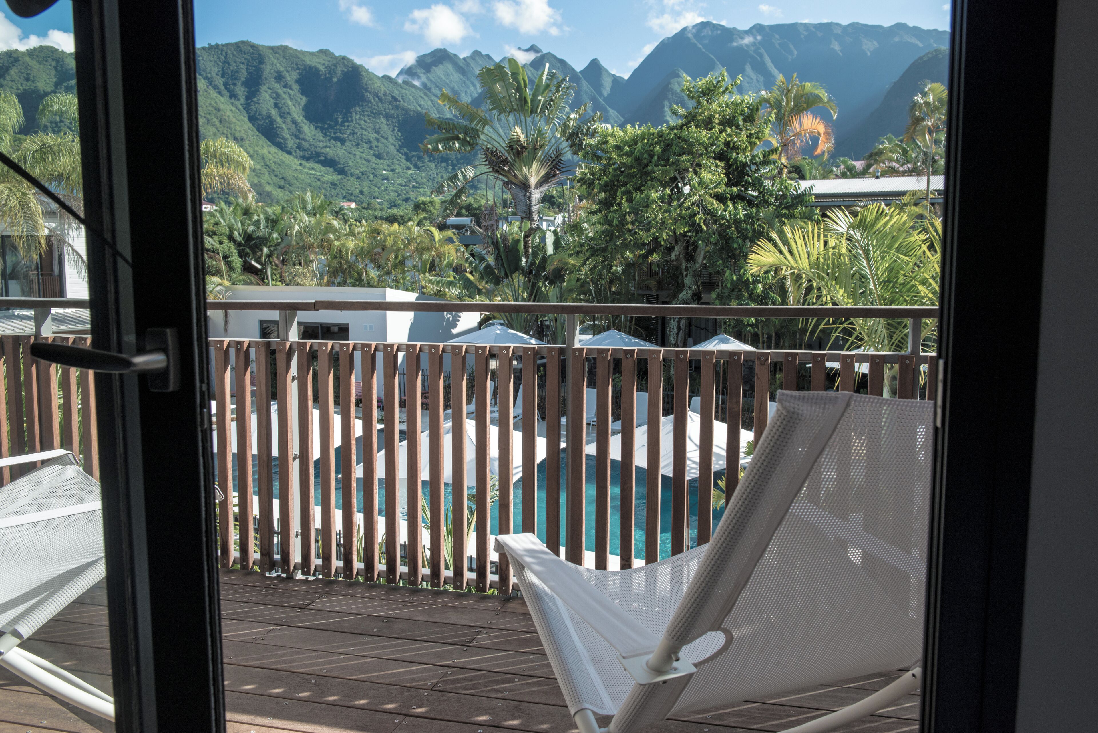 A balcony with a pool, wooden fence, and a view of mountains.