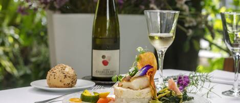 Une table à manger avec une assiette de nourriture, une bouteille de vin et un verre de vin.