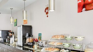 A buffet area with various food options, a coffee machine, and a refrigerator.
