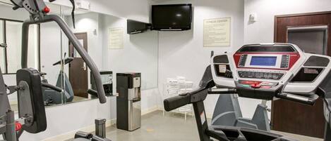 A fitness center with cardio equipment, a treadmill, and a mirrored wall.