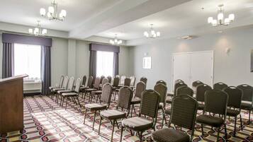 Un salón de conferencias con filas de sillas, un atril y una alfombra estampada.