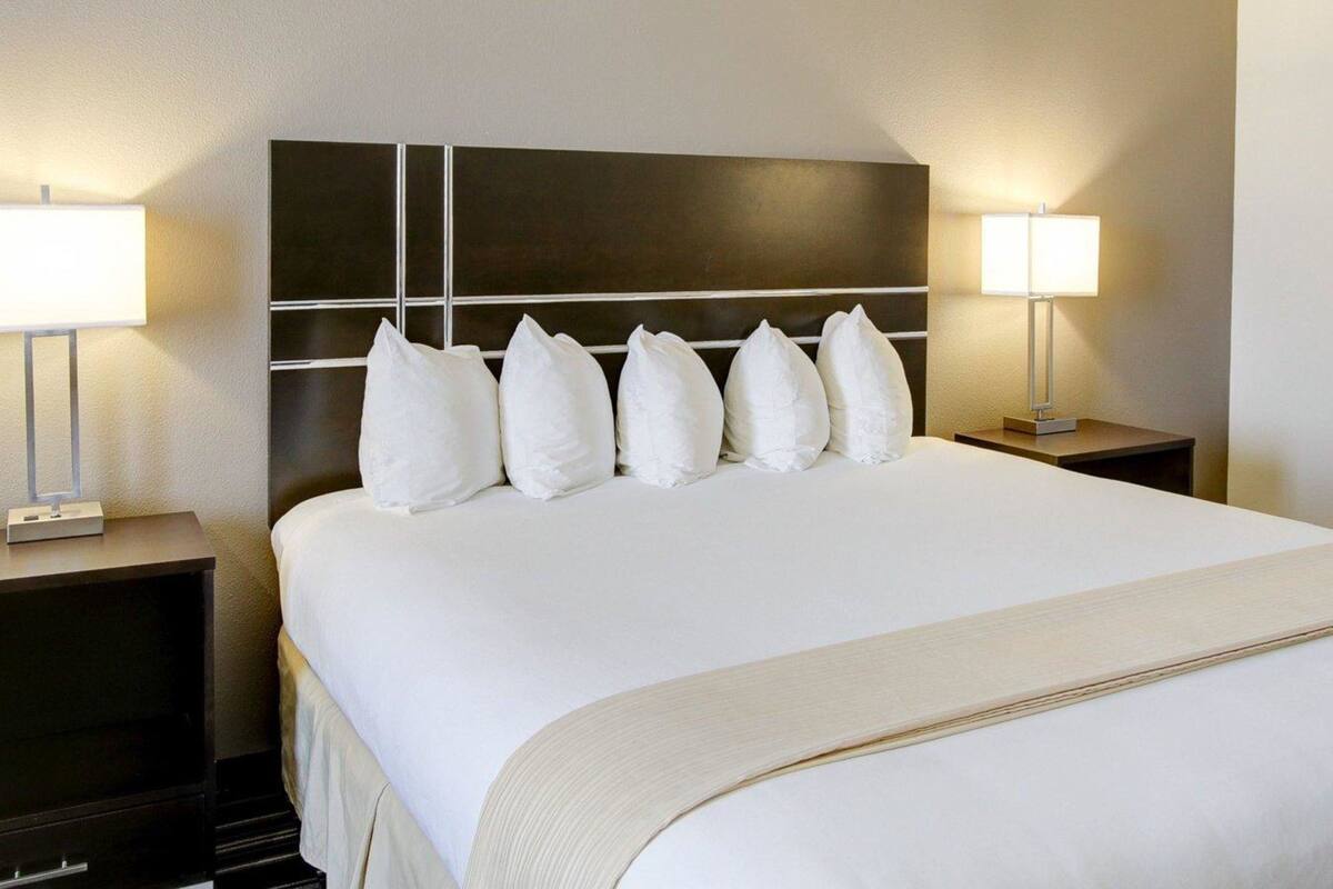 Ett hotellrum med en stor säng, en mörk sänggavel och två sänglampor.