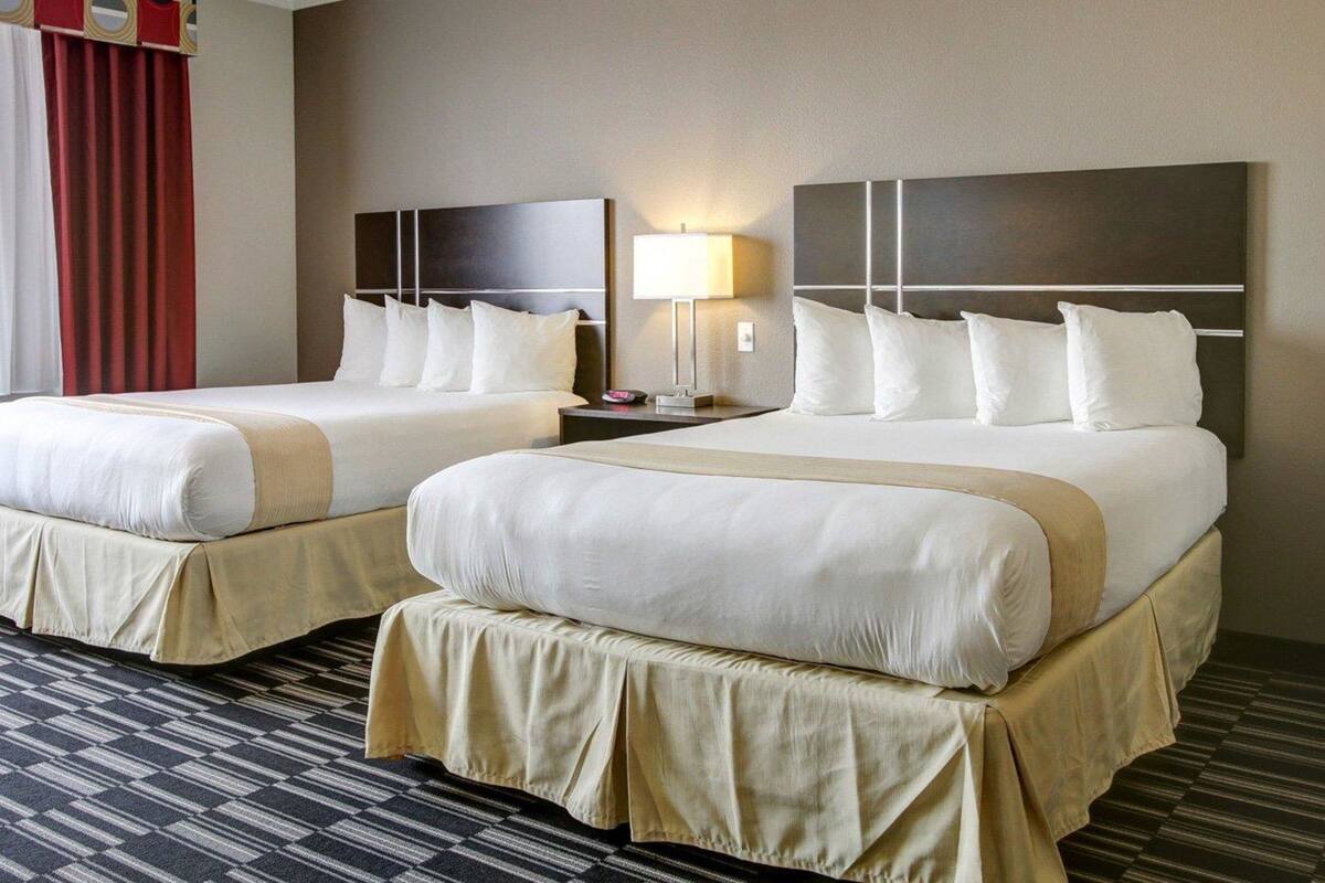 Ett hotellrum med två sängar, en takfläkt, ett sängbord med en lampa och en mönstrad matta.