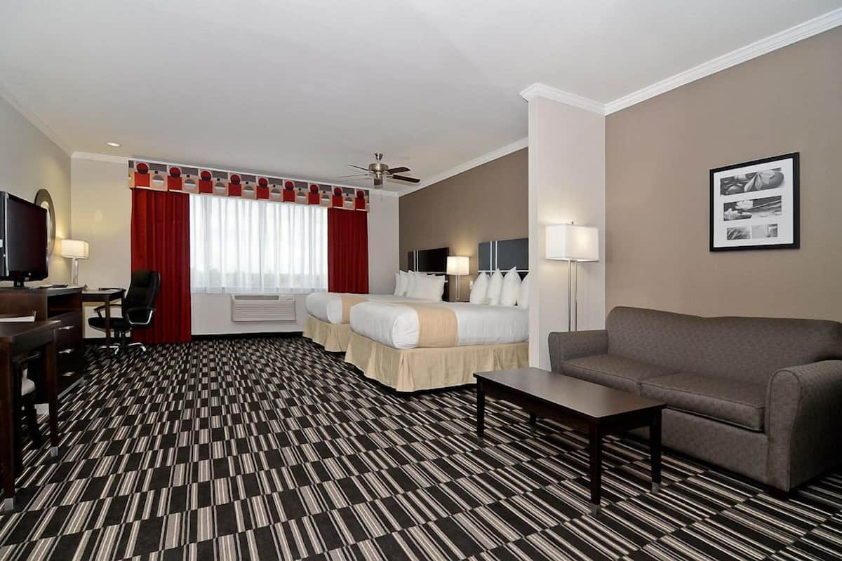 Ett hotellrum med ett mönstrat golv, en säng, en soffa, ett skrivbord och en tv.