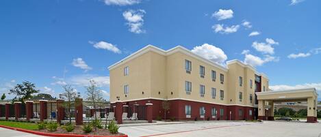 A multi-story hotel with a flat roof, a covered parking area, and a landscaped entrance.