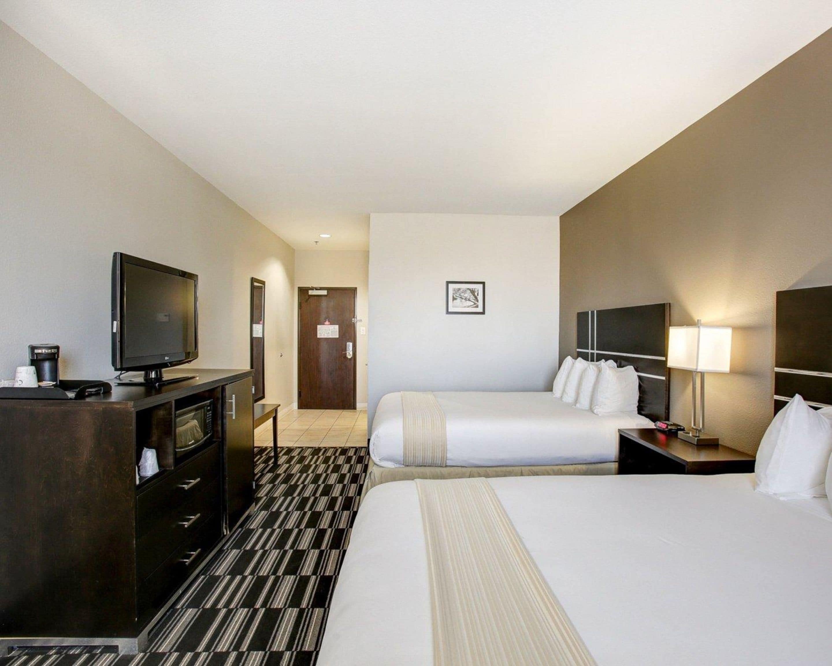 Een hotelkamer met een bed, een televisie, een bureau en een lamp.