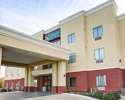 Un hotel con un cartel que dice "Quality Inn & Suites" y una señal que indica una altura libre de 15 pies.