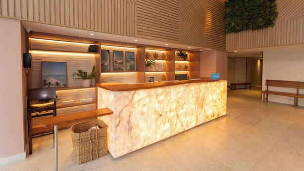A reception area with a marble counter, wooden seating, and a wall-mounted plant.
