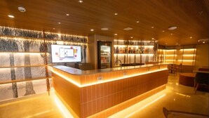 A reception area with a wooden reception desk, a digital display, and a refrigerator.