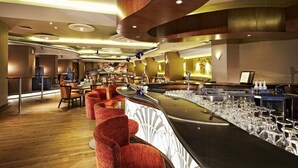 A bar area with a long counter, multiple stools, and a bar stocked with glasses. - éL Hotel Bandung (Bandung)