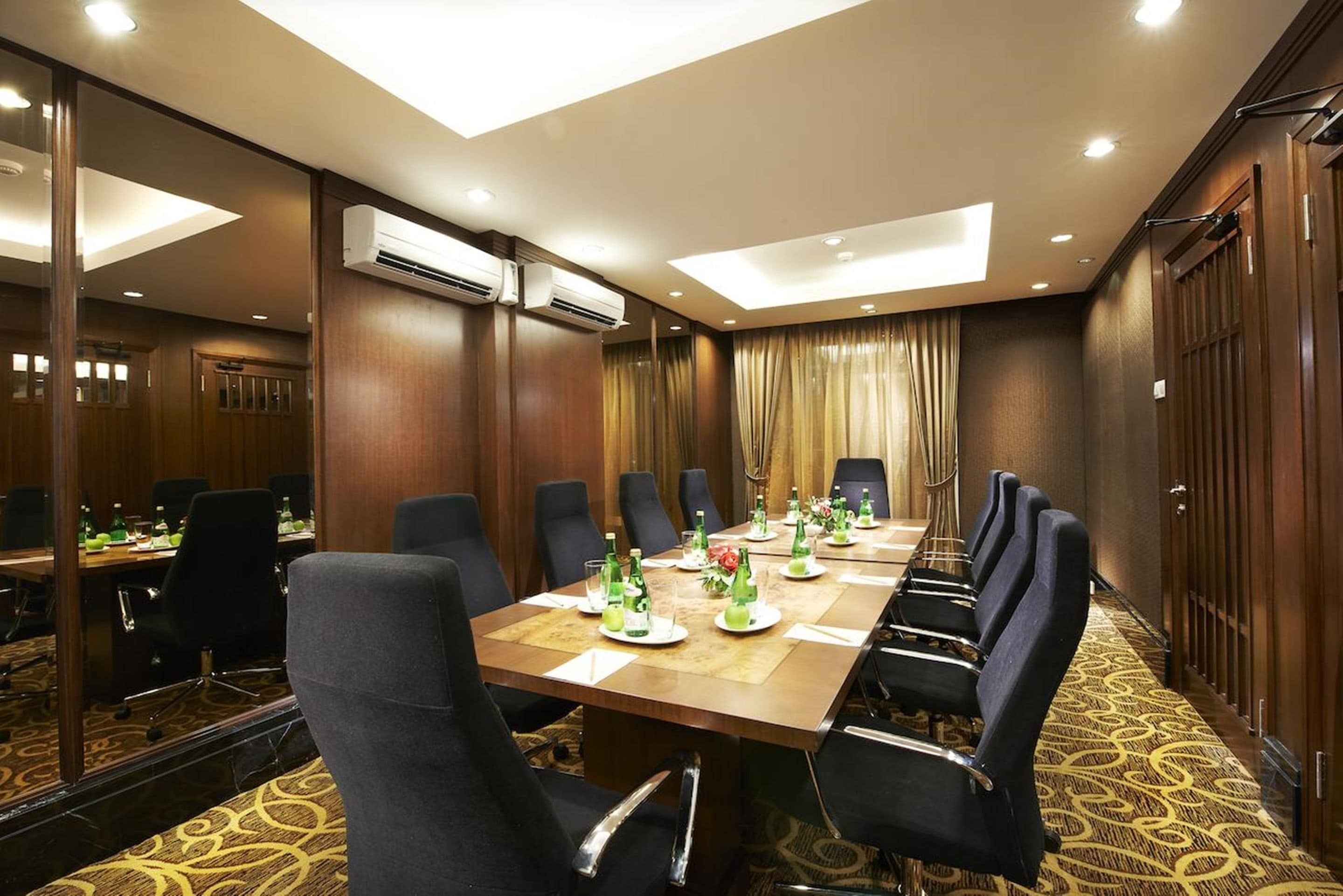 Une salle de conférence avec une longue table, de nombreuses chaises et un grand miroir.