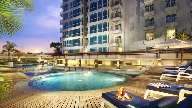 A hotel pool area with a large pool, lounge chairs, and a high-rise building in the background. - éL Hotel Bandung (Bandung)