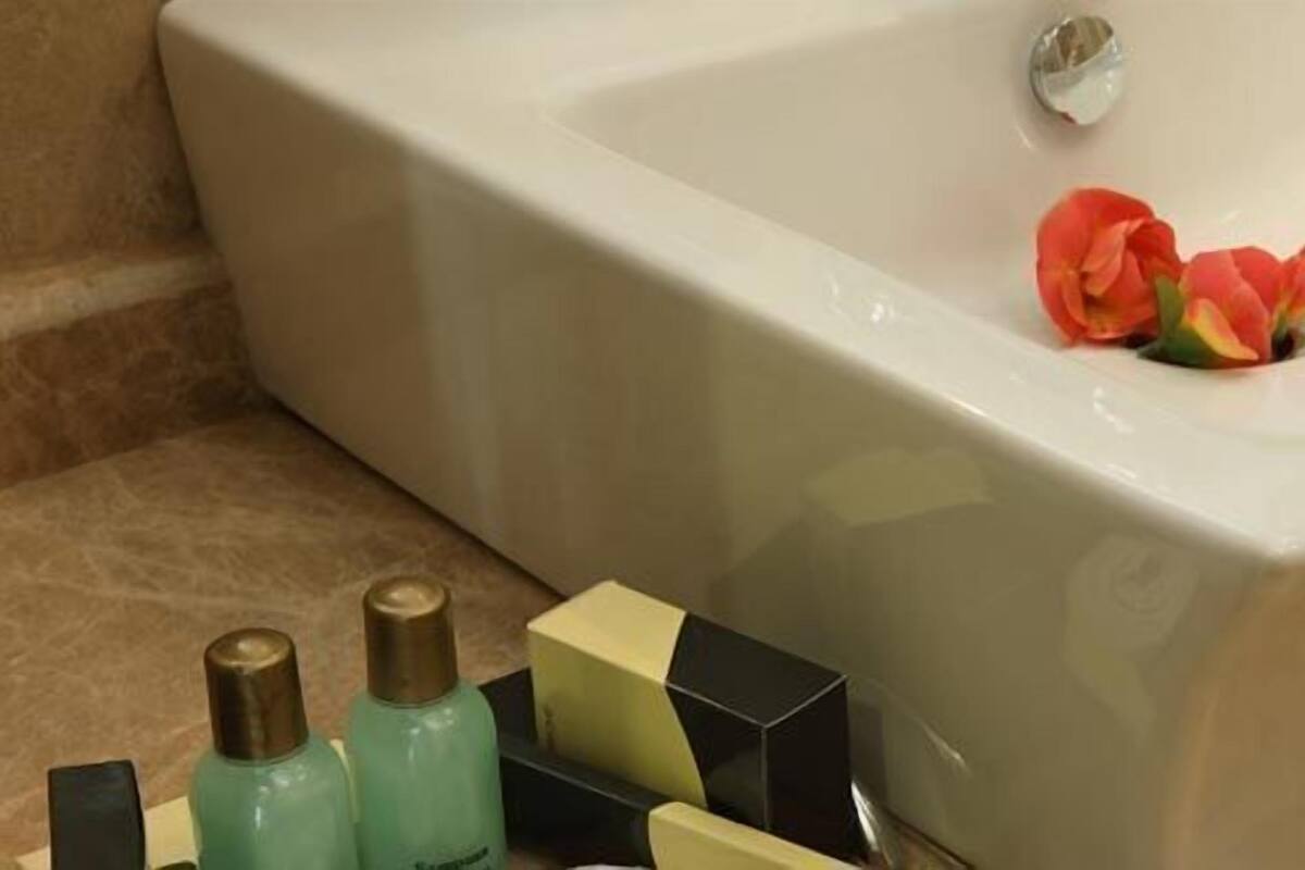 Un baño con una bañera grande, un lavabo y artículos de aseo en la encimera.