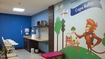 Zona de juegos infantiles con un mural, dispensador de agua y área de descanso.