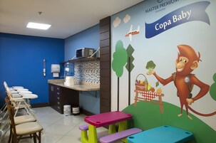 Zona de juegos infantiles con un mural, dispensador de agua y área de descanso.