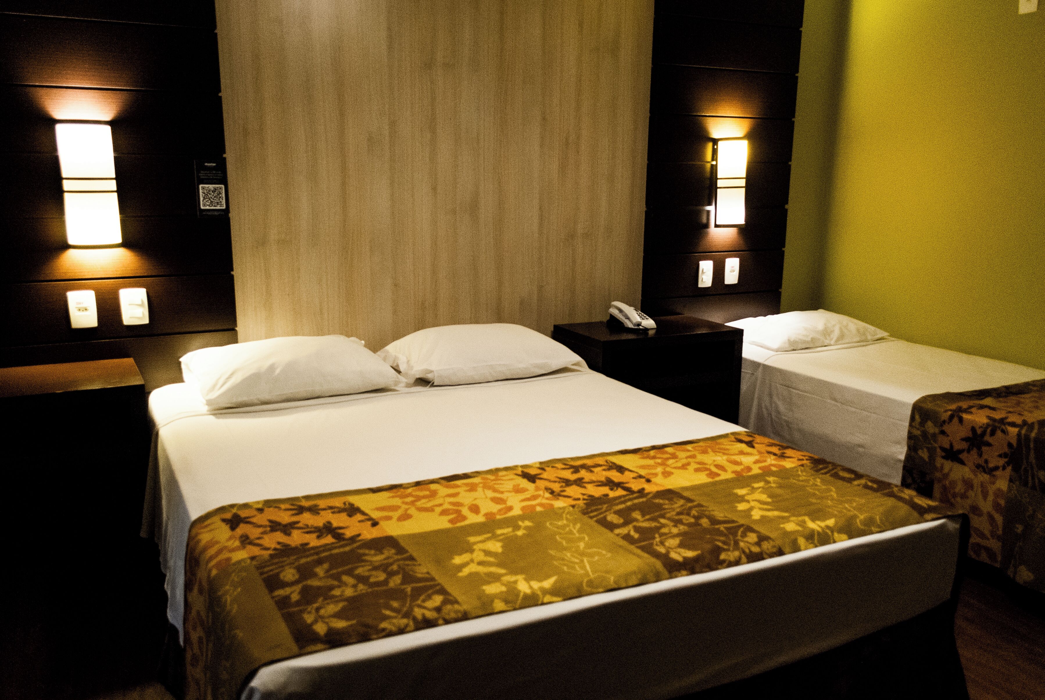 A hotel room with a large bed, two bedside tables, and a nightstand with a phone.