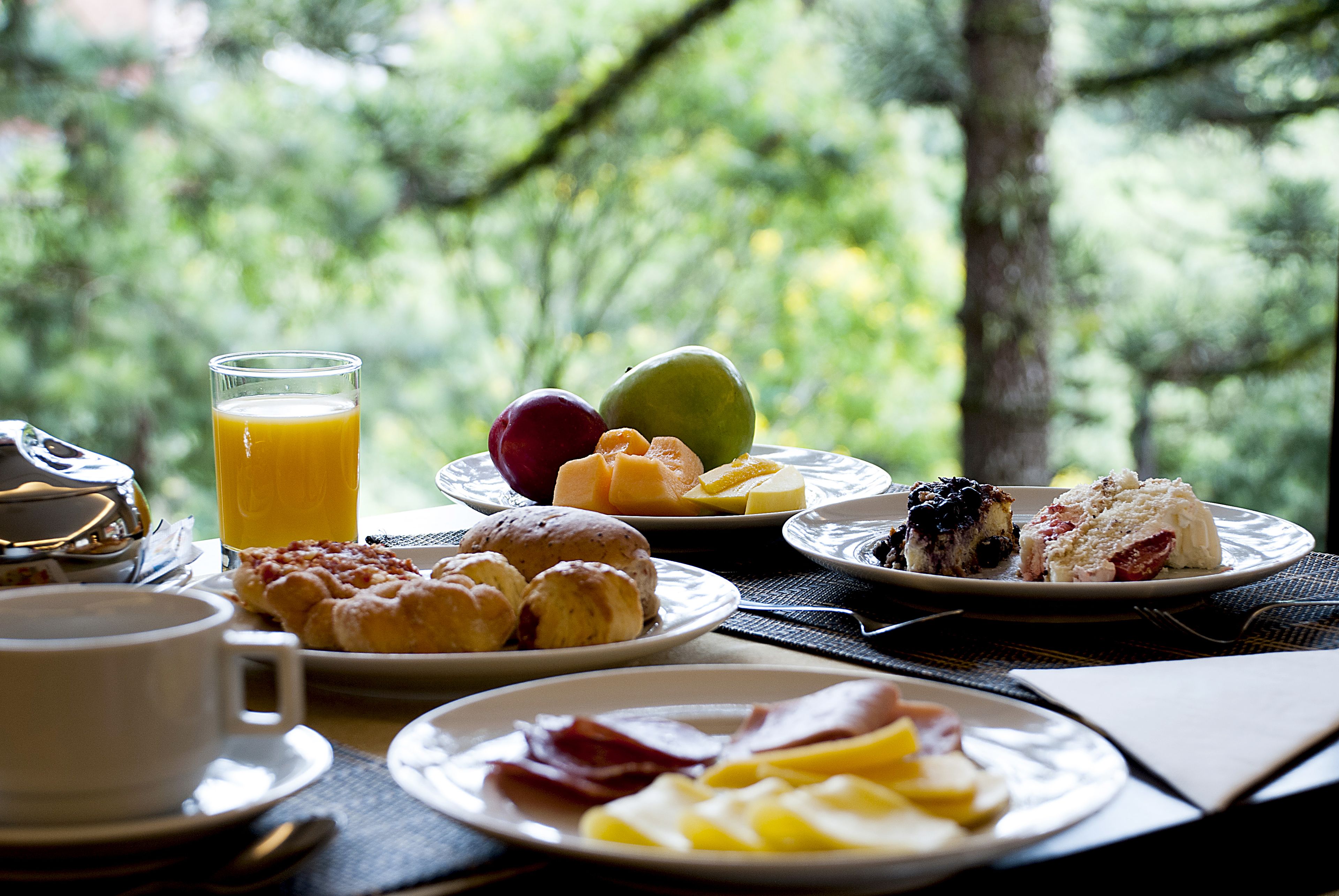 A breakfast table with plates of food, a glass of orange juice, and a cup.