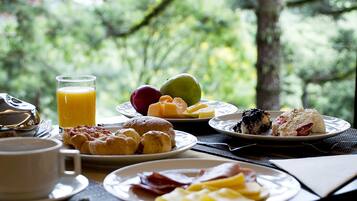 A breakfast table with plates of food, a glass of orange juice, and a cup.