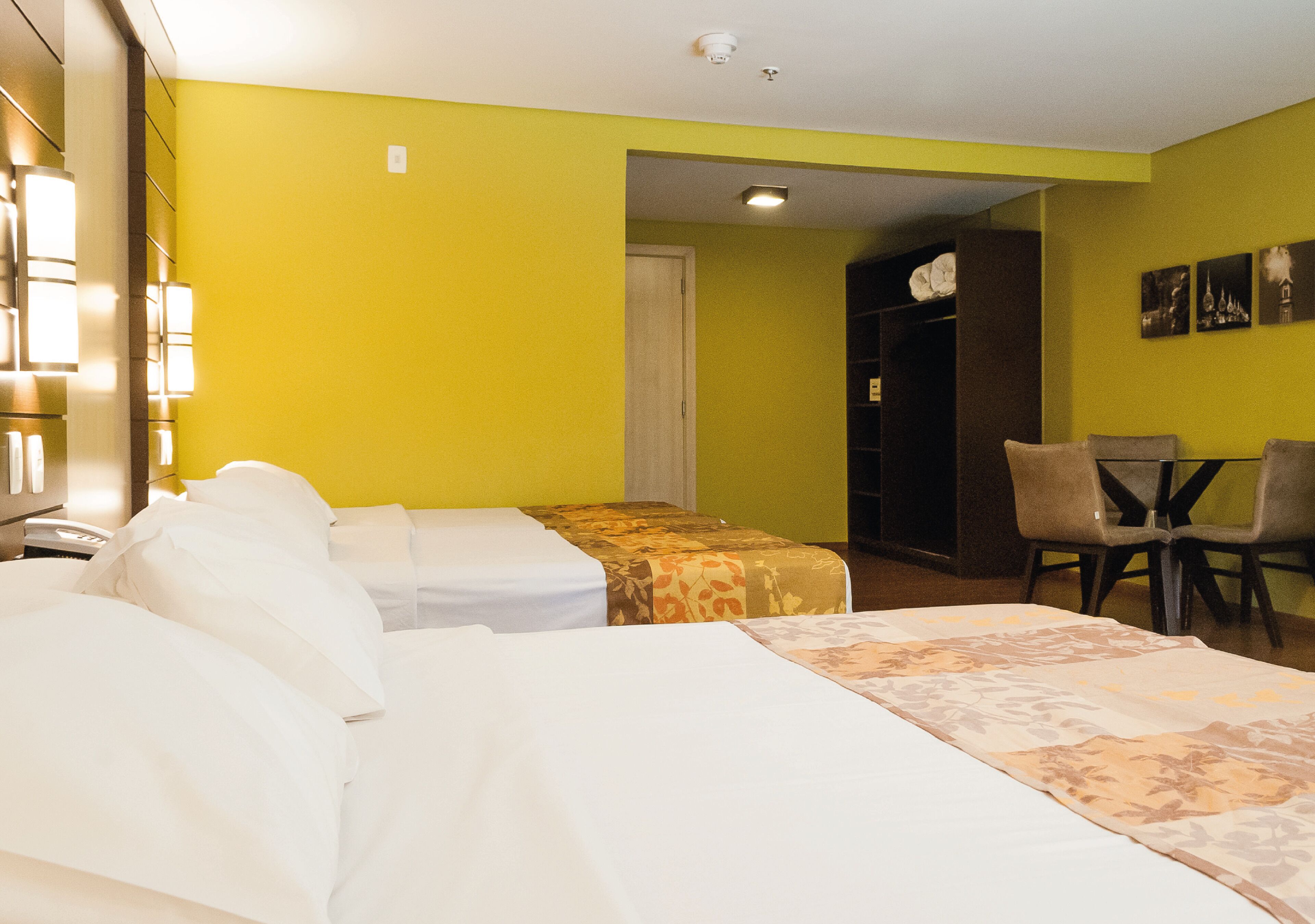 Quarto de hotel com duas camas, uma escrivaninha e uma cadeira.
