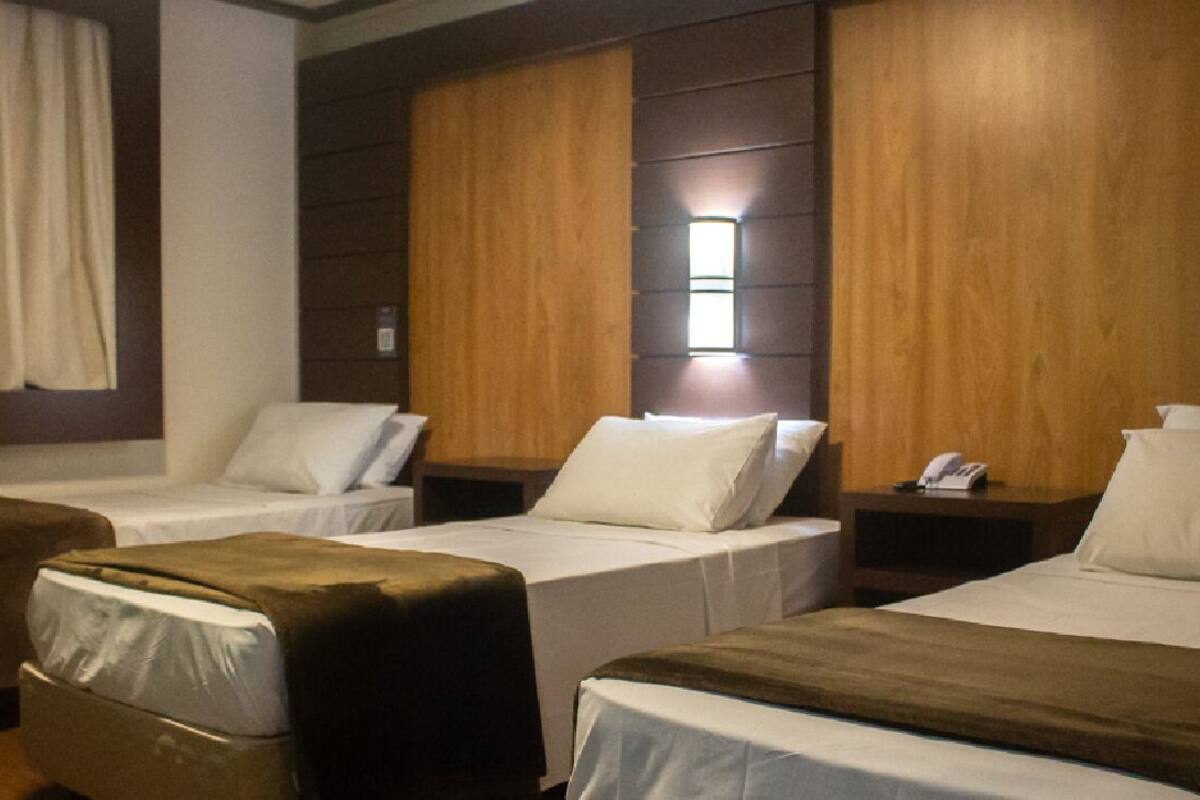 A hotel room with two single beds, a sofa, and a wooden headboard.