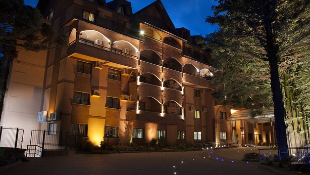 Un hôtel à plusieurs étages, doté d’une façade en briques, de nombreux balcons et d’une entrée bien éclairée.