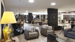 Un hall d’entrée spacieux avec plusieurs coins salon, un comptoir d’accueil et, au fond, un magasin de chaussures.