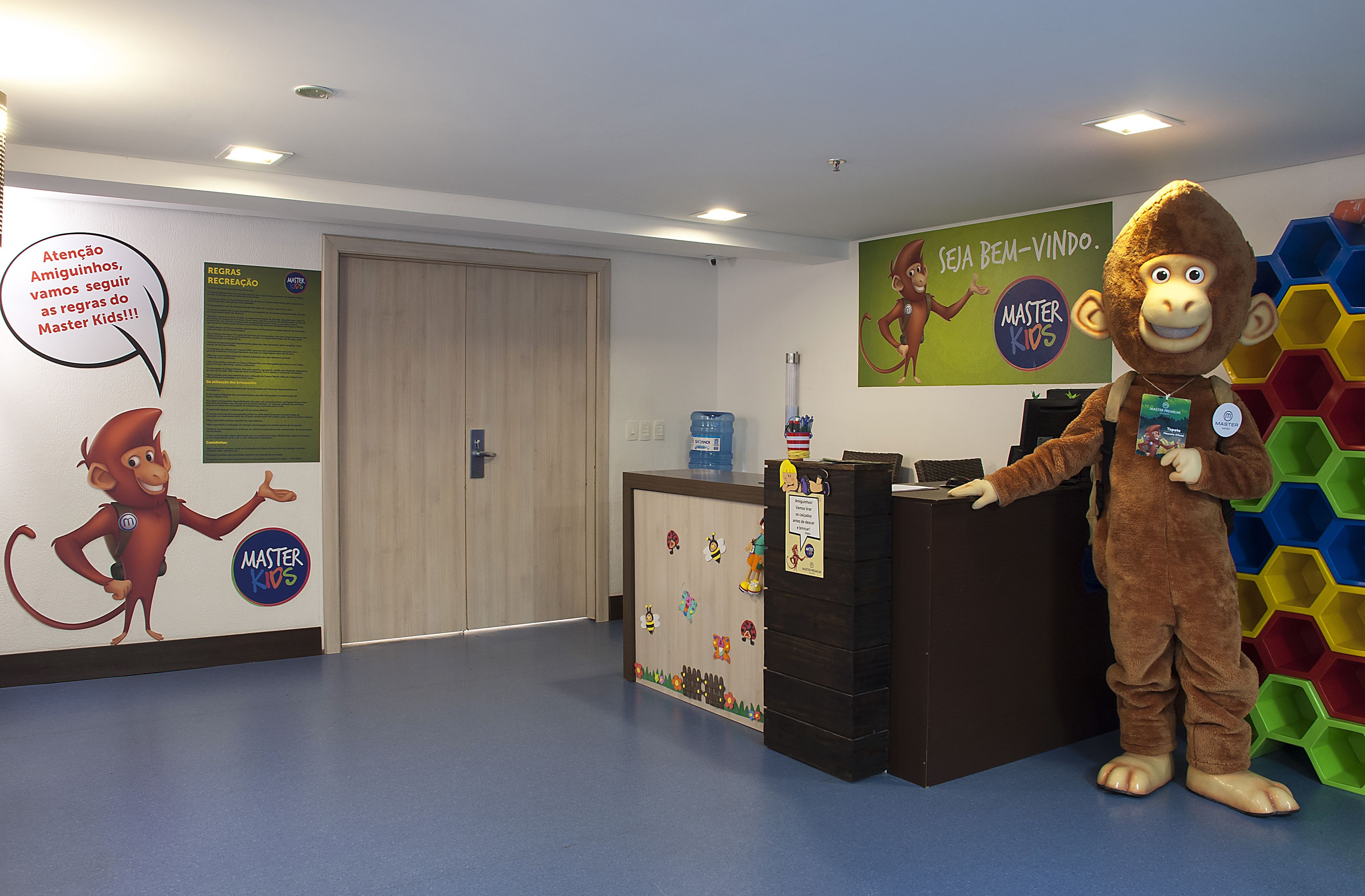 A reception area with a wooden desk, a colorful hexagonal wall decoration, and a cartoon monkey character.