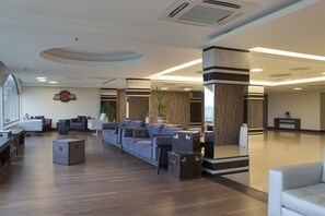 A modern lobby with a sofa, chairs, a clock, and a reception desk. - Master Gramado Hotel (Gramado)