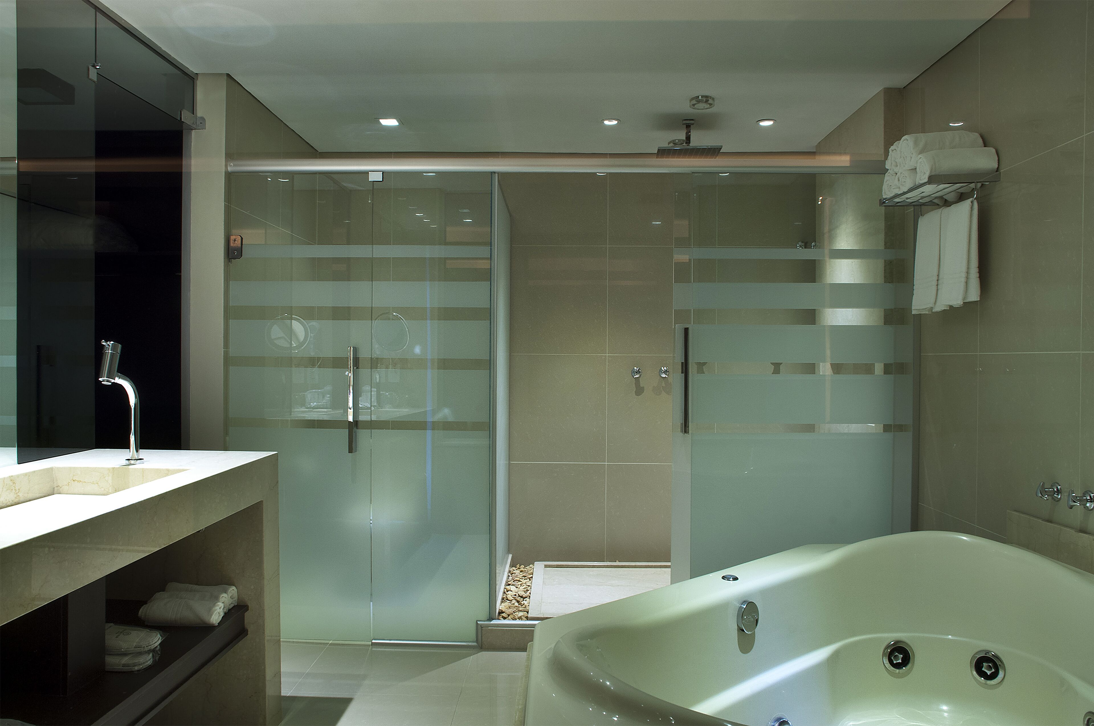 A modern bathroom with a glass-enclosed shower, a freestanding bathtub, and a vanity with a sink and towel storage.