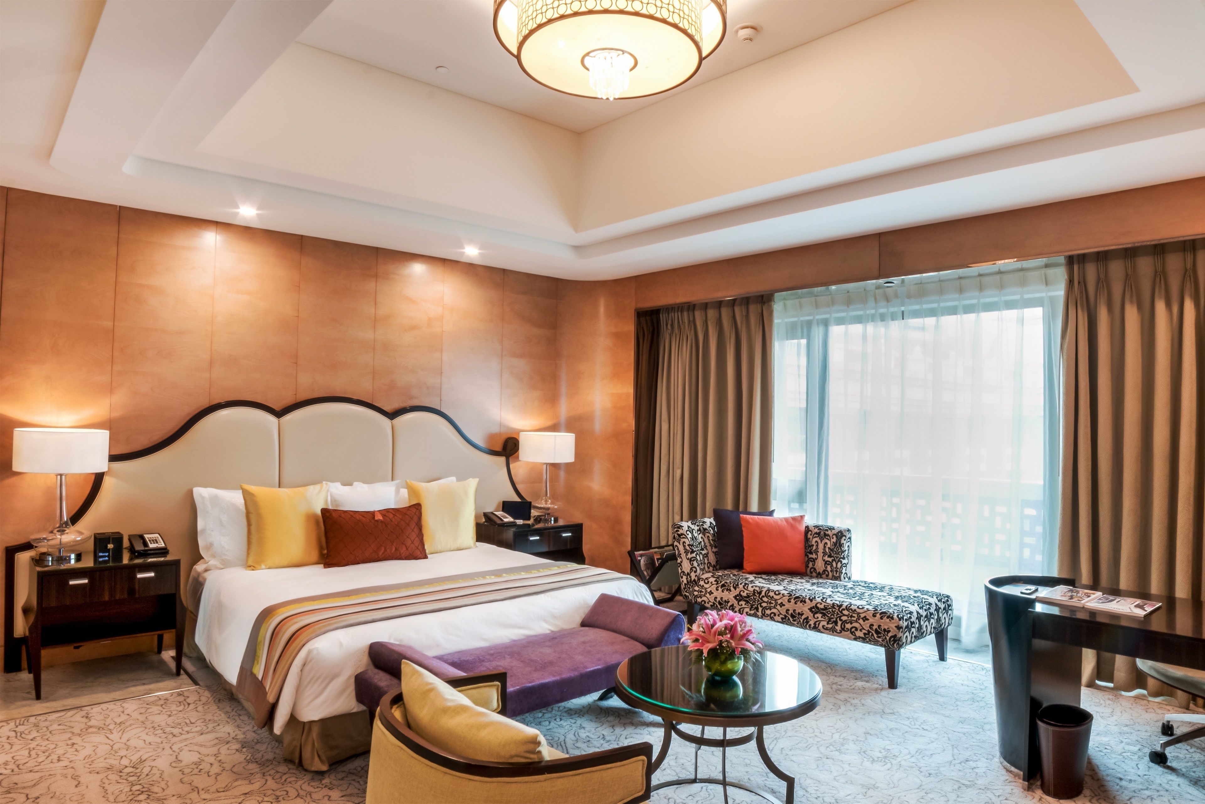 A hotel room with a large bed, a sofa, a small table, and a desk.