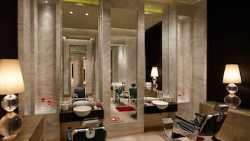 Bathroom features a black barber chair, a white sink, and a vanity with a mirror above.