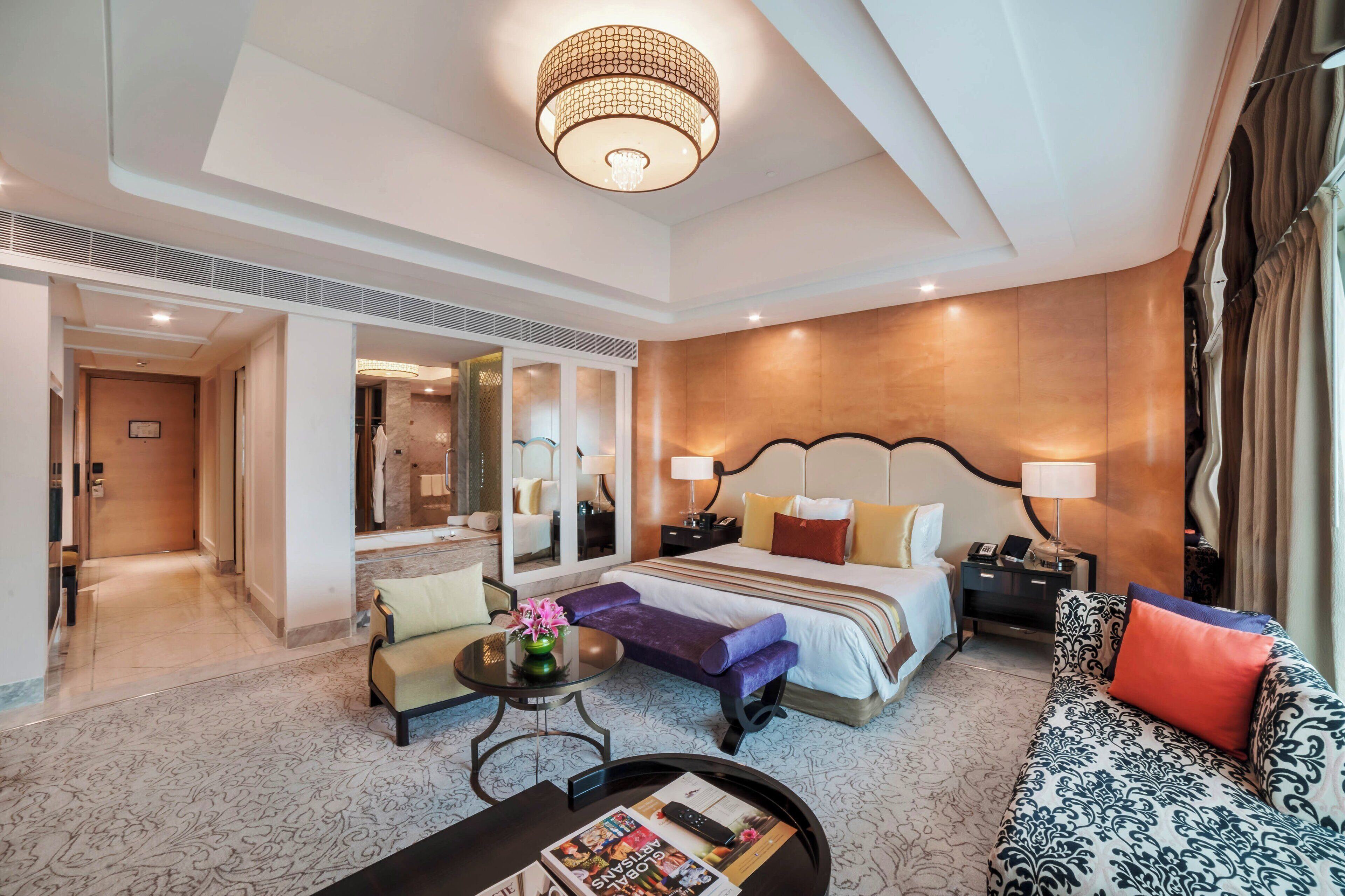Une chambre d’hôtel avec un grand lit, un canapé, une petite table avec un vase et une table de chevet avec une lampe.