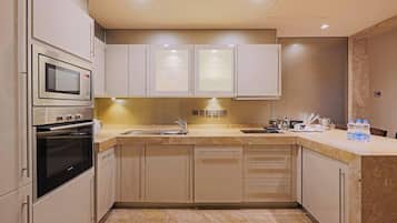 A modern kitchen with built-in appliances, a sink, and a marble countertop.