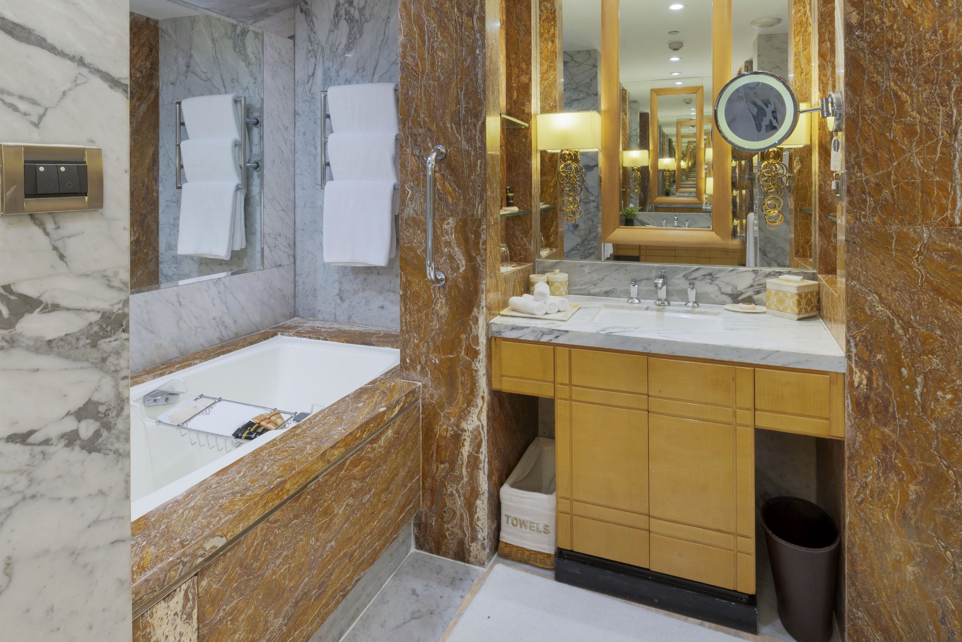 Un baño moderno con lavamanos de mármol, un espejo grande y un perchero para toallas.